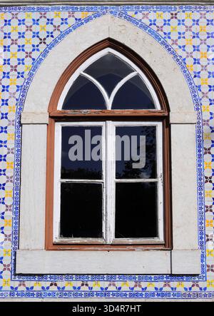 Lisbon, Portugal. Beautiful, old arched wooden window in a marble surround. Facade with typical Portuguese blue and white - azulejo ceramic tiles. Stock Photo