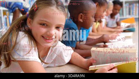 Reading smiling girl holding open book on school carpet, others studying red formulas, copy space Stock Photo