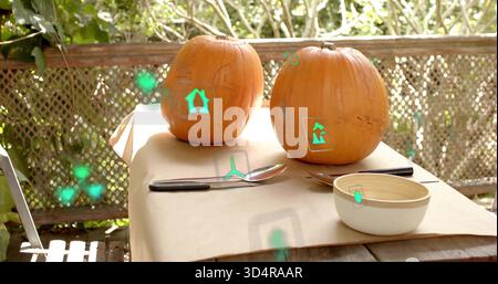 Sitting two orange pumpkins showing stencil marks on kraft-covered patio table, with green AR icons Stock Photo