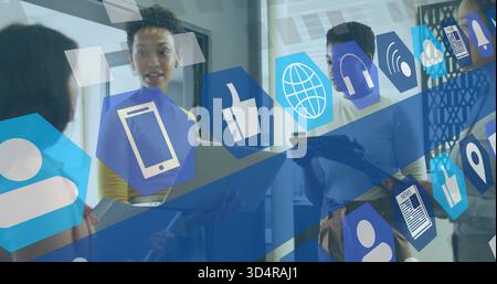 Discussing four women talking near glass wall holding laptop in yellow top under digital overlay Stock Photo