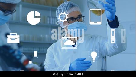 Inspecting male technician wearing PPE holding amber flask to eye level in lab with overlay icons Stock Photo