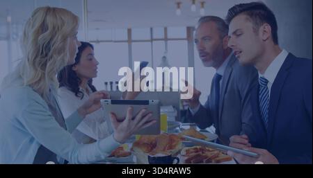 Presenting woman in cardigan holding tablet, colleagues in suits gesturing, coffee and croissants Stock Photo