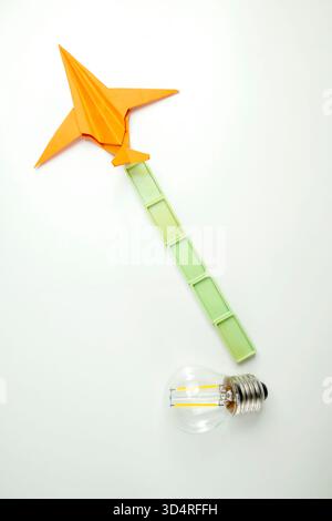Top view of a lightbulb with rectangular blocks and a paper airplane on a white background. Concept of travel, exploration, and navigation Stock Photo