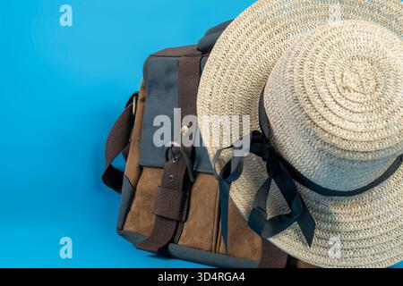 Canvas bag and a straw hat with a black ribbon on a blue background. Concept of travel, summer, or vacation Stock Photo