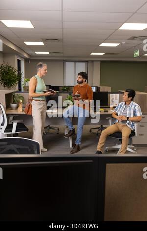 Collaborating diverse coworkers analyzing details in open-plan office, with tablet and notebooks Stock Photo