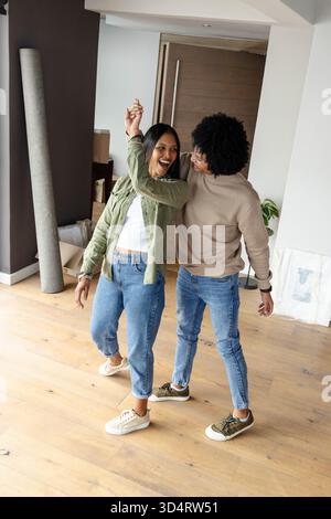 Dancing African American couple laughing and spinning in new apartment, with moving boxes Stock Photo