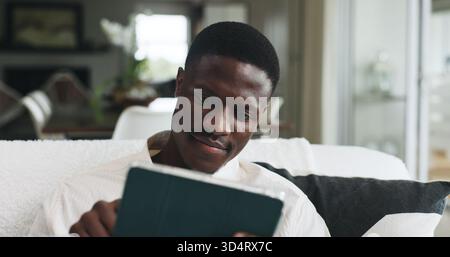 Freelancer, tablet and research with black man on sofa for editor feedback, blog writer or reading. Online review, report and remote worker or person Stock Photo