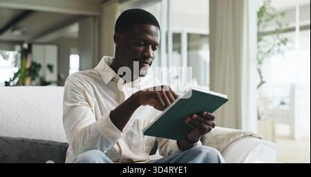 Freelancer, tablet and typing with black man on sofa for editor feedback, blog writer and research. Online review, report and remote worker or person Stock Photo