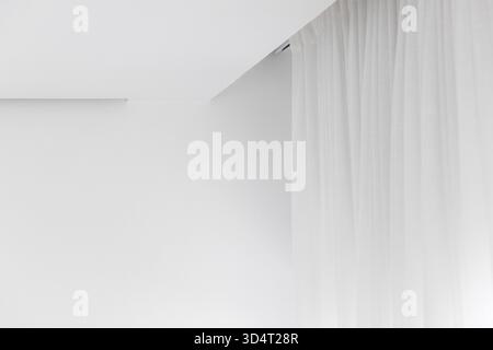 A bright, minimalist white space features a soft curtain along the right edge, creating a calm atmosphere and clean lines. Ideal for modern, serene in Stock Photo