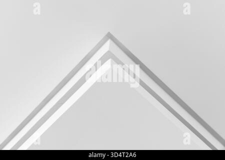 A close-up of a white architectural corner forming a sharp pyramid, emphasizing clean lines, symmetry, and soft shadows. This abstract image conveys m Stock Photo