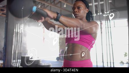 Lifting woman holding kettlebell at gym, wearing pink sports bra and leggings, smartwatch, HUD Stock Photo