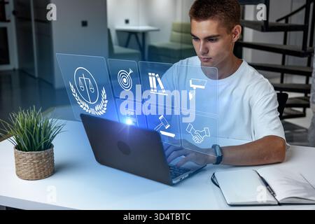 Young man working on laptop with holographic screen in modern workspace setting Stock Photo