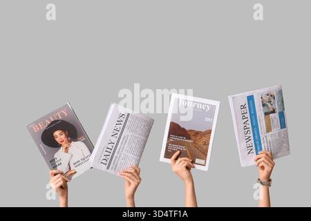 Female hands with different magazines and newspapers on grey background Stock Photo