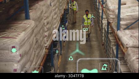 Walking warehouse workers in safety vests checking warehouse aisle, with sacks, drums and AR icons Stock Photo