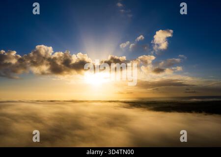Aerial view of the sun piercing through clouds, casting a golden glow over the landscape, Henley-on-Thames, Oxfordshire, United Kingdom. Stock Photo