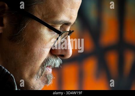 Intense portrait of a man's face, focused sharply against a highly blurred, graphic backdrop. Suitable for themes of business, thought, and personalit Stock Photo