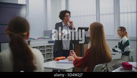 Female Educator in Computer Programming Class Presents Software Code on Smartboard, Engaging Students in Discussion. Concept STEM Education, Interactive Learning, and Innovation in Teaching Methods. Stock Photo