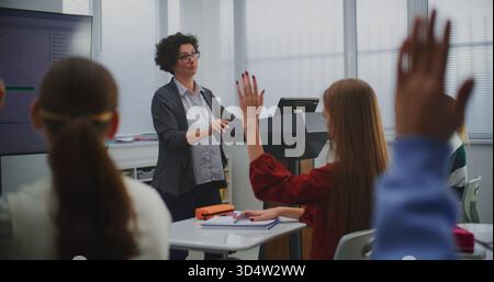 Female Educator in Computer Programming Class Presents Software Code on Smartboard, Engaging Students in Discussion. Concept STEM Education, Interactive Learning, and Innovation in Teaching Methods. Stock Photo