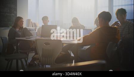 Diverse Group of Students Gathers Around Central Table, Working Together Intensely on Laptops. Collaboration, Group Project Work, and Essential Role of Digital Learning in Modern Educational Setting. Stock Photo