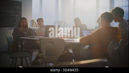 Diverse Group of Students Gathers Around Central Table, Working Together Intensely on Laptops. Collaboration, Group Project Work, and Essential Role of Digital Learning in Modern Educational Setting. Stock Photo