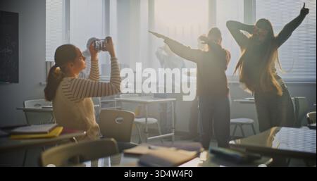 Girl Films Two Female Classmates Smiling and Performing Trendy Dance Moves on Smartphone. Concept of Digital Generation, Teamwork, Joyful Interaction Between Students and TikTok Trend. Static Shot. Stock Photo