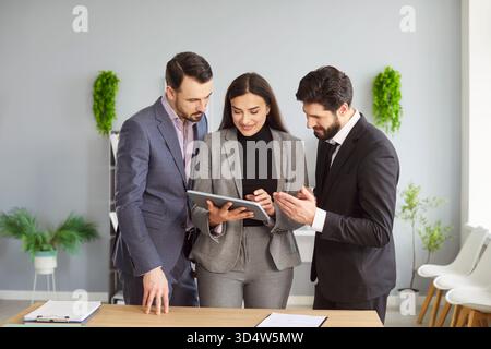 Group of business people discussing project and financial data while using digital tablet in office. Stock Photo