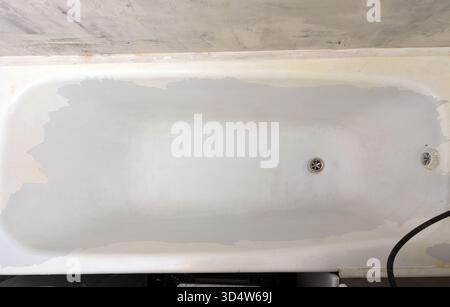Top view of a worn bathtub under renovation, showing faded paint and exposed edges, ideal for concepts of home improvement and bathroom repair. Stock Photo