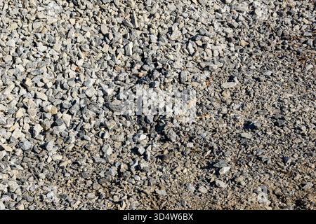 Layer of angular gray gravel shows progress in site preparation with uneven coverage indicating ongoing work, selective focus Stock Photo