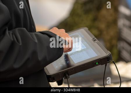 A man in a dark jacket uses a secure tablet to control military systems Stock Photo