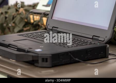 An outdoor rugged laptop on an army desk is used in the field Stock Photo