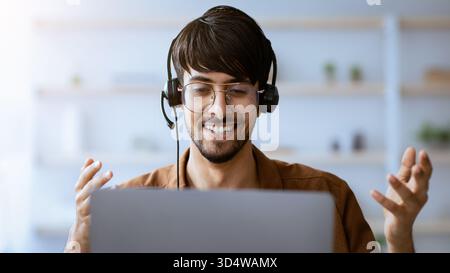 Young Man Enjoying a Virtual Meeting While Wearing a Headset at Home Stock Photo