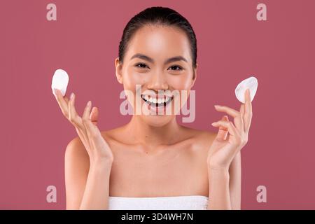 Young Korean Woman Smiles While Holding Cotton Pads During Her Face Care Routine at Home Stock Photo
