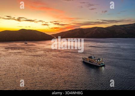 Yasawa Islands, Fiji - 20 October 2025: Aerial view of a cruise ship sailing on calm waters, embraced by the silhouettes of distant islands under a vi Stock Photo