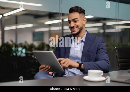 Happy Middle Eastern Businessman Using Digital Tablet in Modern Office Environment Stock Photo
