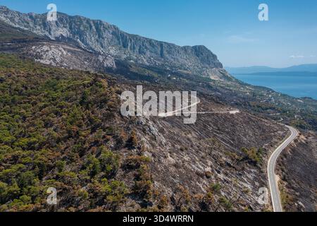 Aerial view of scorched earth meets the azure sea, a stark contrast on the slopes of Biokovo, Republika Srpska, Bosnia and Herzegovina. Stock Photo
