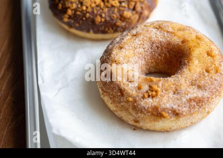 Close-Up of Chocolate-Covered and Biscuit-Topped Donuts Displayed on a Metal Tray Stock Photo