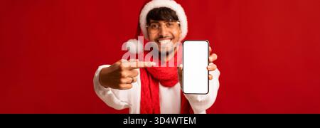 Smiling Man in Festive Attire Showcasing a Blank Phone Against a Red Backdrop for Holiday Promotions Stock Photo
