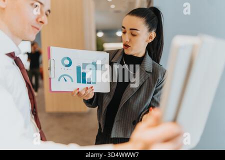 Multicultural business presentation in office as woman presents charts and graphs to colleagues Stock Photo