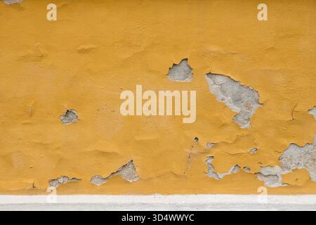 Orange painted concrete wall with paint falling off and worn down Stock Photo