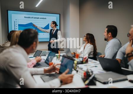 Presenter leads a business meeting as colleagues review a chart and discuss data in a conference room Stock Photo