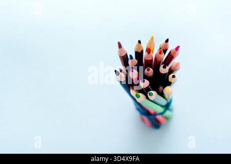 Colored pencils, scissors, notebook, ruler, pen, eraser, sharpener and more in glass. School and office stationery on light blue background. Concept back to school. Top view. Stock Photo