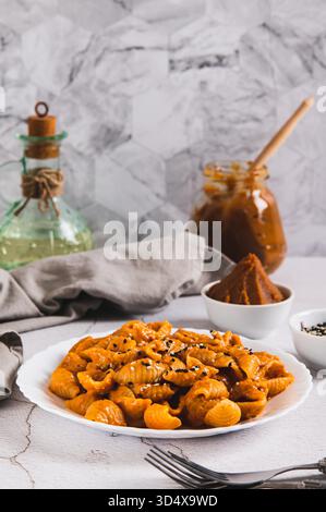 Spicy miso pasta shells on a plate on the table vertical view Stock Photo