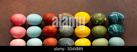 Brightly colored Easter eggs are arranged in a grid, displaying shades like pink, blue, green, and yellow. These eggs symbolize renewal and are often part of festive gatherings, banner Stock Photo