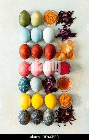Brightly colored Easter eggs , showcasing various hues created from natural dye sources. Fresh ingredients are displayed alongside such as beets, turmeric and hibiscus, cabbage and onion peel, vinegar Stock Photo
