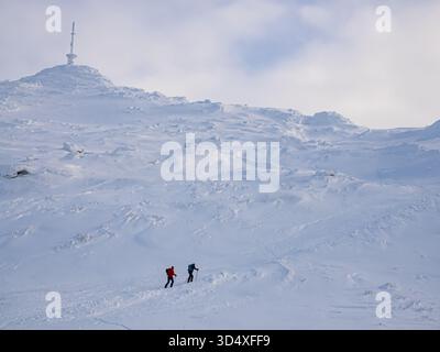 Ski-touring - two skiers in colorful jackets climb to the top of a mountain in the Narvikfjellet ski resort in Narvik. Lapland, Norway, Northern Europ Stock Photo