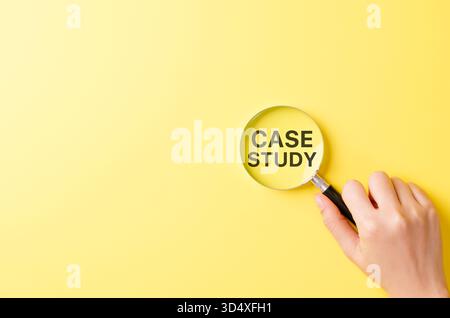 Case study research concept, hand holding magnifying glass focusing on bold text CASE STUDY over yellow background symbolizing detailed investigation, Stock Photo