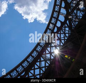 Sun rays shining through Eiffel Tower lace. Colorful beams and spots. Paris, France. Stock Photo