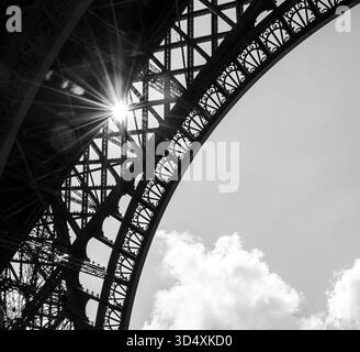 Sun shining through Eiffel Tower. Paris, France. Black white historic photo. Stock Photo