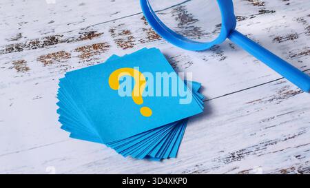 Question Mark Search: Stack of Blue Sticky Notes and Magnifying Glass on Wood Stock Photo