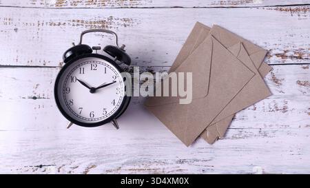 Time Sensitive Communication: Vintage Alarm Clock Next to Stack of Brown Kraft Envelopes Stock Photo